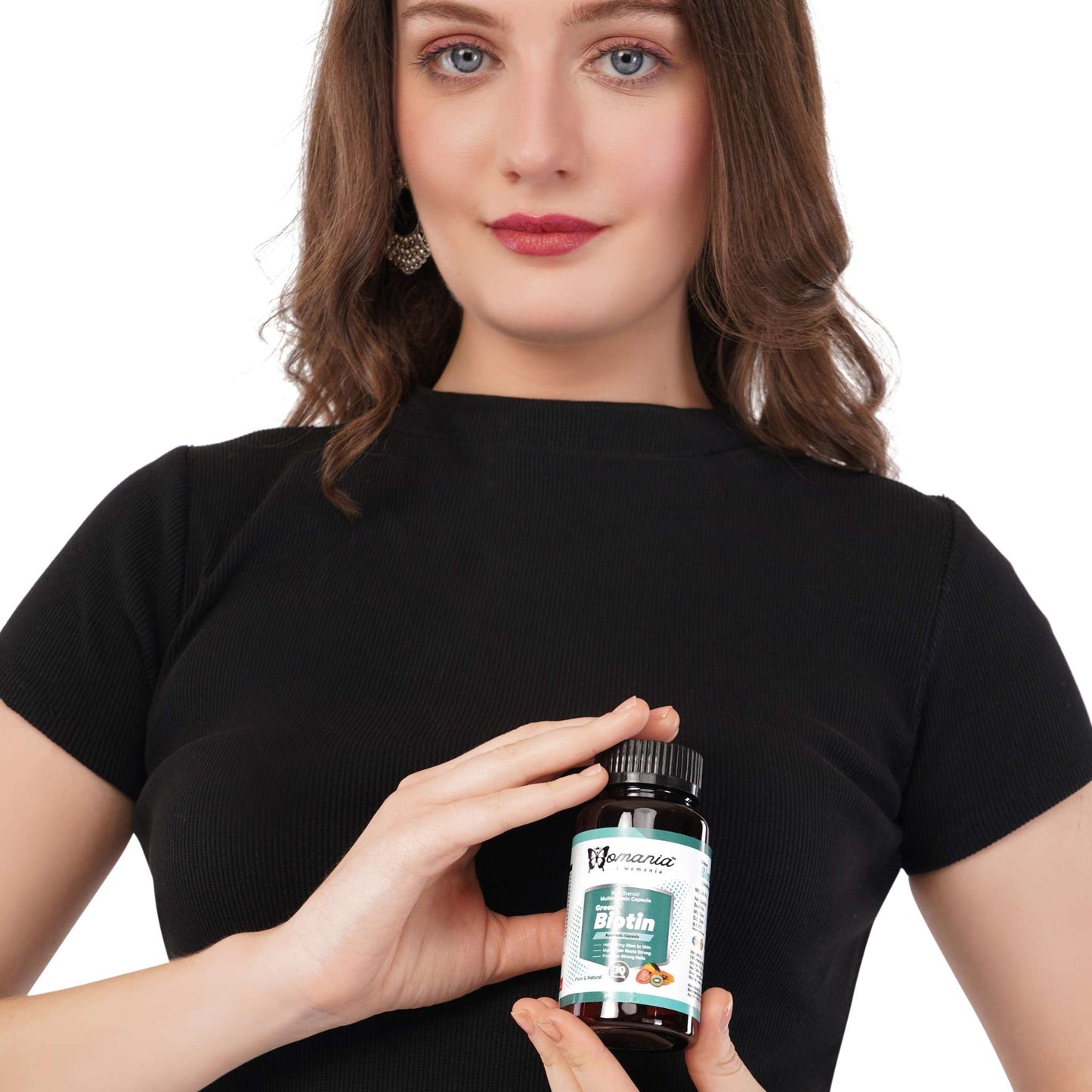Green Biotin capsules for hair, skin, and nail health held by a woman.