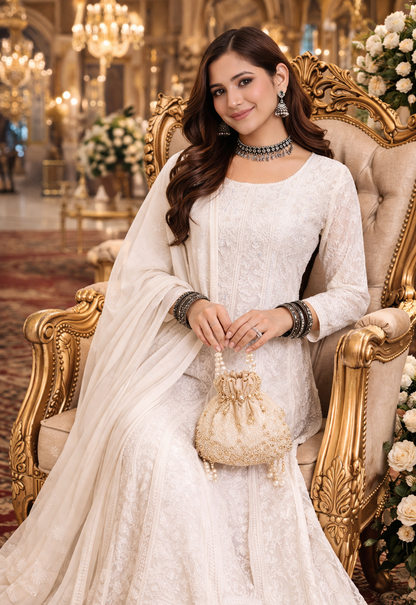 Lucknowi Chikankari Anarkali suit worn by a model seated elegantly, showcasing hand embroidery and a graceful silhouette.